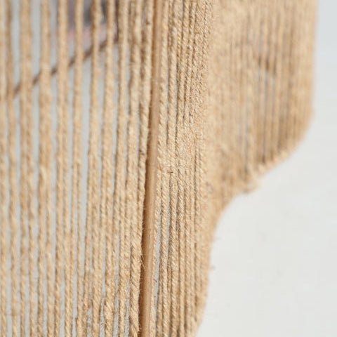 Primer plano de Aplique de pared en yute y hierro Yaxunah con tela texturizada beige y líneas verticales sobre una superficie clara, mostrando texturas naturales del yute para un toque orgánico.