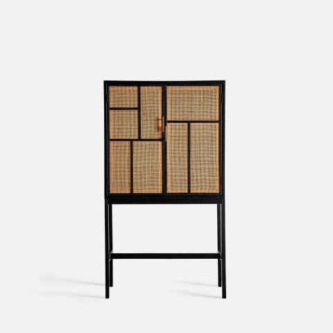 El armario de madera de pino y ratán Beilen presenta un diseño rectangular con un marco de madera negra, puertas de ratán tejido y cuatro patas delgadas, que ofrecen un almacenamiento compacto sobre un fondo blanco liso.