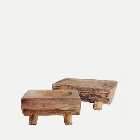 El centro de mesa en madera de caoba Akviran C presenta dos pedestales rústicos de madera rectangulares con patas cortas, elaborados en diseño artesanal, que se muestran sobre un fondo blanco liso.