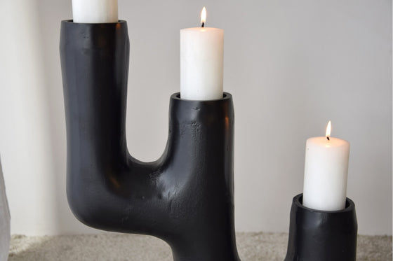 El Candelabro Totem N.1 Metal Negro 3 Velas, con tres velas blancas encendidas en un diseño negro en forma de cactus, ejemplifica el diseño contemporáneo al tiempo que agrega un toque de elegancia a cualquier espacio.