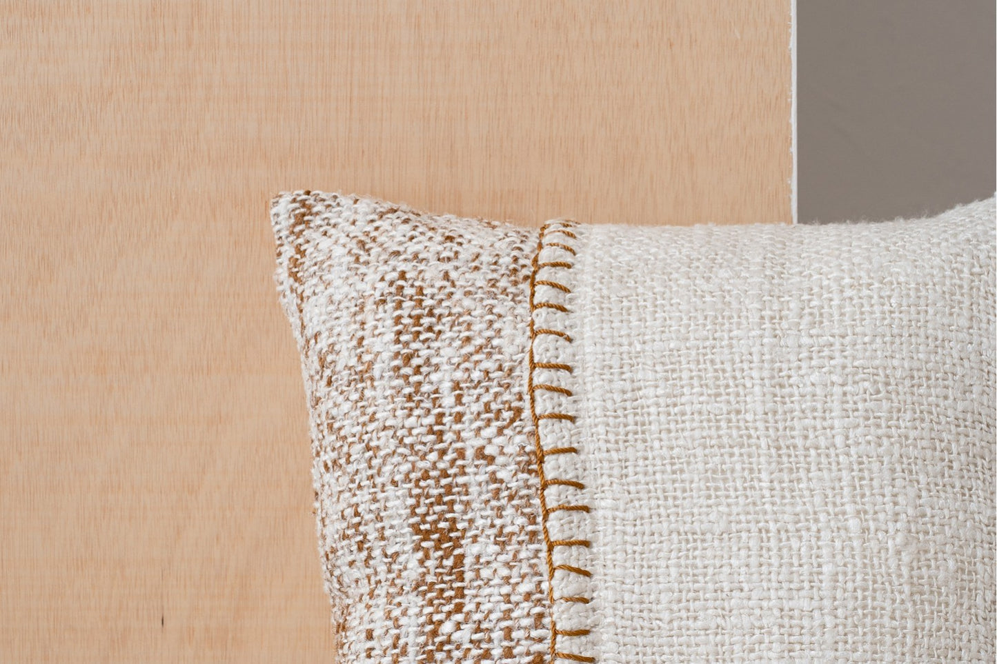Primer plano del Cojín de algodón blanco y marrón con franja bordada 50X50CM - natural - ANXA N1 mostrando las costuras visibles, sobre un fondo de madera clara y gris.