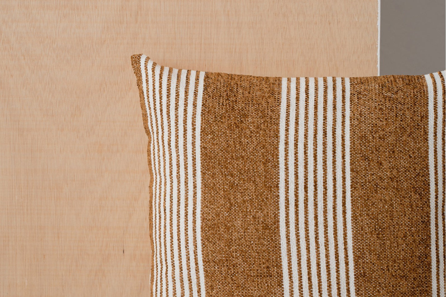 Detalle del Cojín de algodón blanco y ocre con franjas 50X50CM - natural - MINIA N1, con rayas marrones y blancas, sobre un fondo de madera clara.