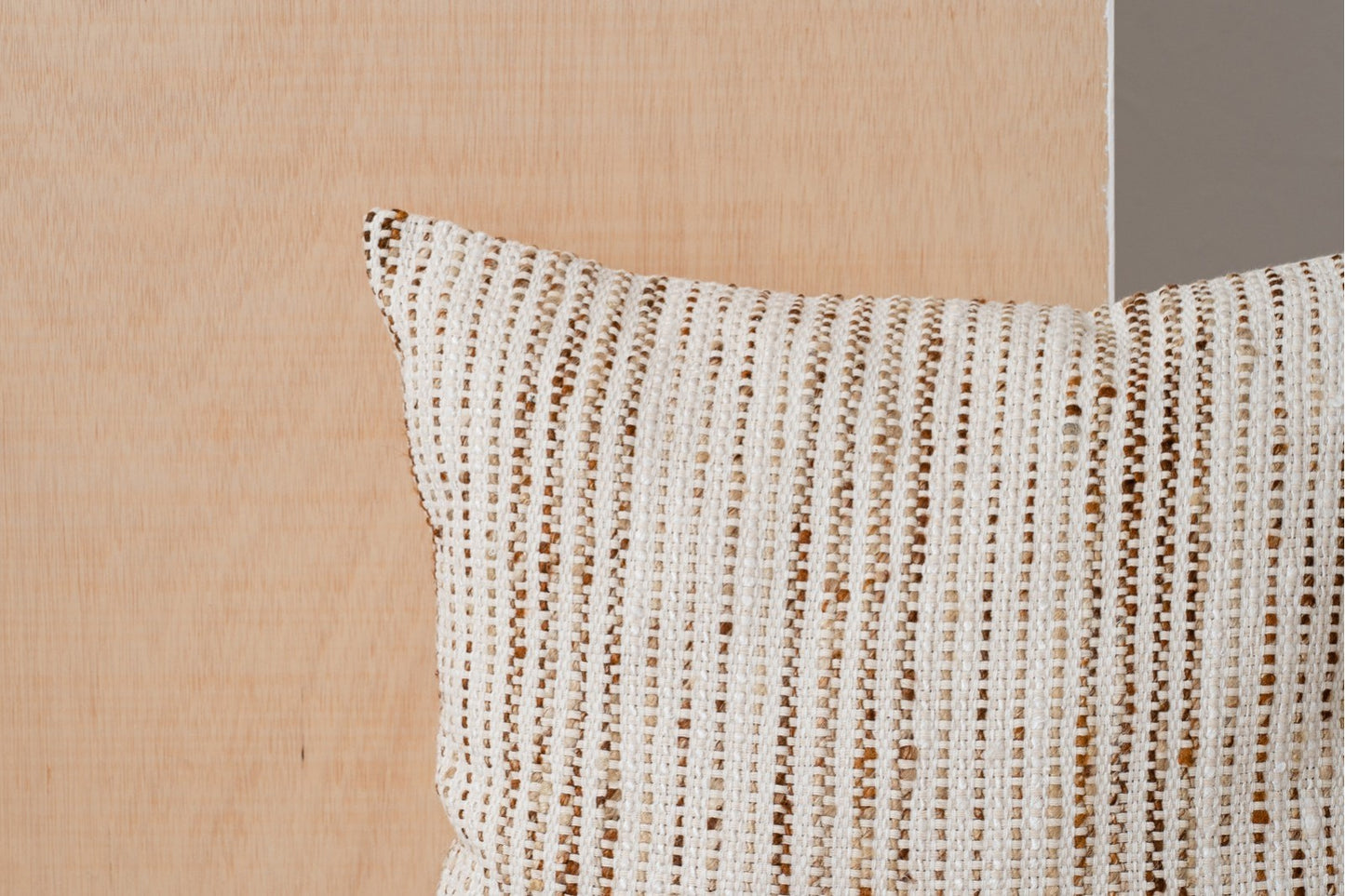 Primer plano del Cojín de algodón blanco, ocre y beige con líneas 50x50CM - natural - MINIA N2 sobre un fondo de textura de madera clara.
