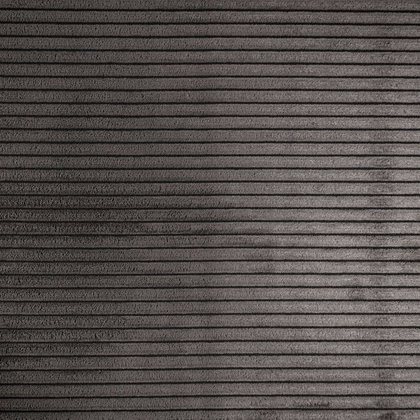 Superficie gris texturizada con líneas horizontales espaciadas uniformemente, haciendo eco del aspecto moderno del Puff grande de foam y terciopelo acanalado 110×100×74 cm - SNUG 100 WAVES para salón o dormitorio.