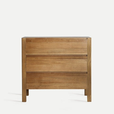 A Cómoda de madera DM estriada Copenhague con tres cajones, textura acanalada horizontal y diseño moderno sobre fondo claro. Ideal para almacenamiento elegante en cualquier espacio.