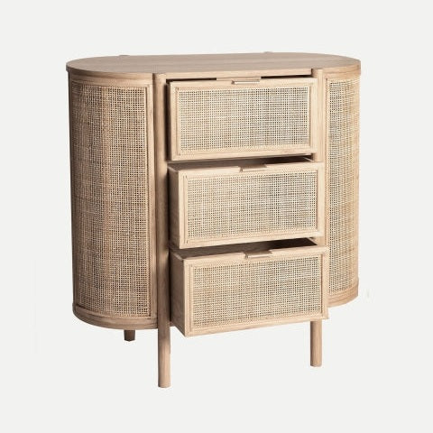 La Cómoda en madera de mango y ratán IKLA presenta tres cajones parcialmente abiertos y paneles de ratán tejido en el frente y los laterales, aportando un toque natural y un diseño minimalista.