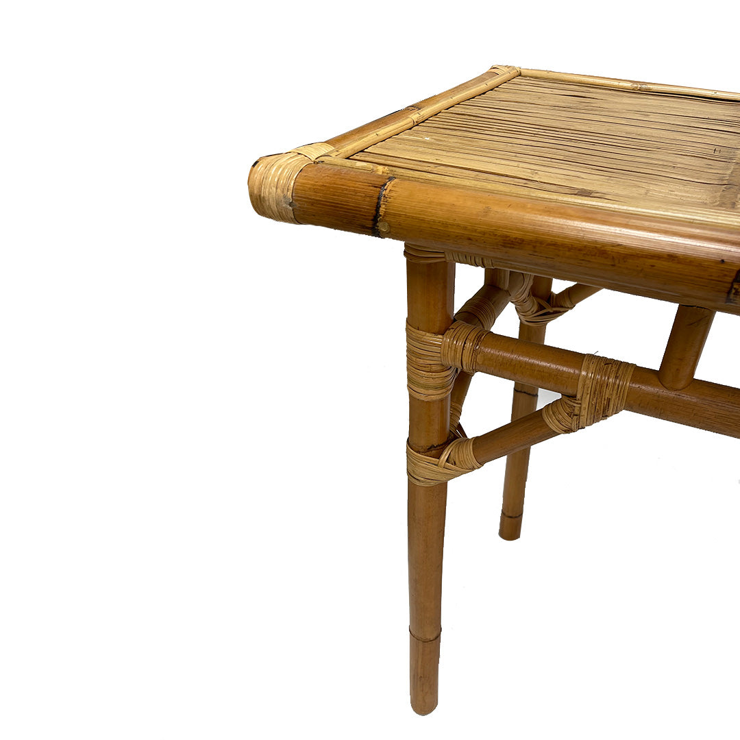 Un primer plano de la Consola en Bambú y Ratán Kalua muestra sus detalles tejidos en bambú y ratán, destacando parte del tablero, las patas y la estructura de soporte sobre un fondo blanco.