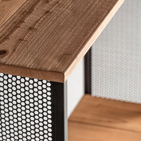 Primer plano de la consola esquinera Gien, que presenta una tapa de madera de abeto y laterales de hierro de malla hexagonal negra que enfatizan la textura natural de la madera y el encanto industrial de su diseño de malla.