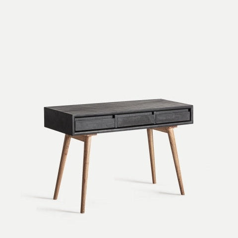 La Consola en madera de mindi Thiers es un escritorio moderno con una tapa rectangular oscura, tres cajones frontales y cuatro patas en ángulo hechas de madera de mindi, que se muestran sobre un fondo claro y liso.