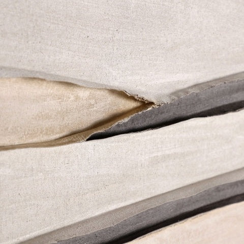 Primer plano de los bordes de láminas de tela apiladas y superpuestas de color beige y gris con pliegues y costuras, que evocan el arte abstracto, ideal como pieza central para decoración moderna. Cuadro decorativo abstracto en lienzo (120x150 cm) Valeria.