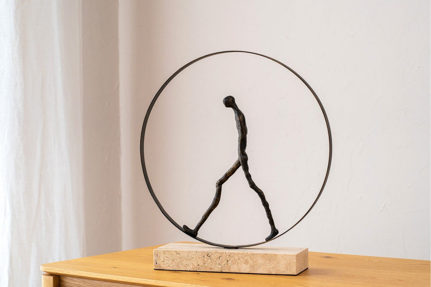 La "Escultura de metal - mármol - bronce envejecido - moderna - CAMINANDO EN CIRCULO" presenta una figura humana minimalista en un marco circular sobre base de mármol-una pieza decorativa moderna ideal para cualquier espacio.