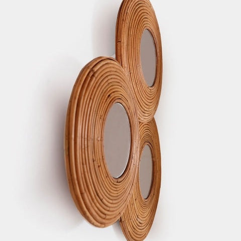 El Espejo circular de bambú eco Asher 3 cuenta con tres espejos de pared redondos con marcos de ratán tejido, elaborados con bambú natural, dispuestos sobre un fondo blanco para un toque de diseño colonial.