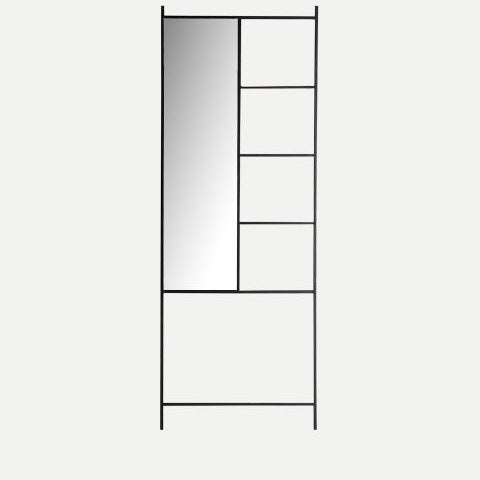Un marco alto de metal negro con el Espejo rectangular en hierro negro (66x180 cm) Ezequiel a la izquierda y cuatro estantes abiertos a la derecha crean un ambiente industrial y un diseño contemporáneo sobre un fondo claro y liso.