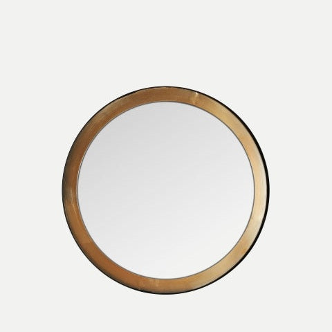 El espejo circular en hierro y madera Jacou, de marco dorado y delgado inspirado en el diseño art decó, destaca sobre un fondo claro y minimalista.
