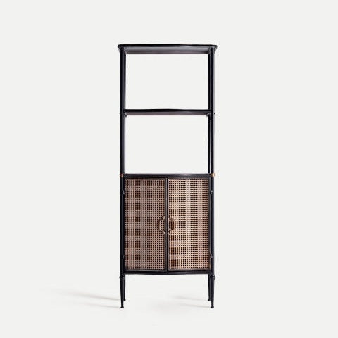 La Estantería en hierro con armario Elstob, alta y negra, tiene dos estantes abiertos superiores y un armario inferior con puertas de ratán tejido y tiradores metálicos, fusionando elegancia industrial y diseño contemporáneo.