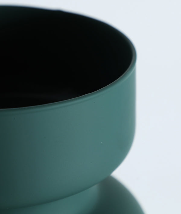 Detalle del Jarrón de vidrio verde mate 18×18×36 cm - moderno - SKARA, un jarrón cilíndrico de color verde azulado mate con una superficie lisa y curvada, sobre un fondo claro liso.