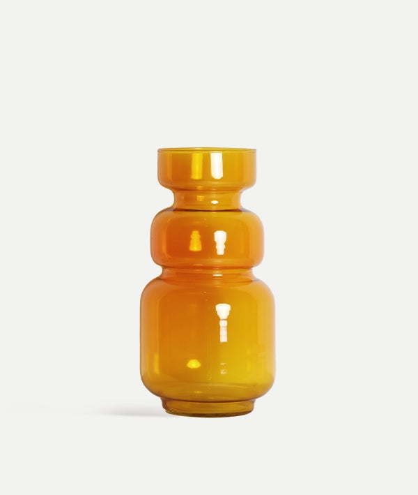 El jarrón de vidrio ámbar brillo 17×17×35 cm SOLANGE, de diseño moderno y geométrico, destaca con su acabado brillante y forma cilíndrica sobre un fondo blanco.