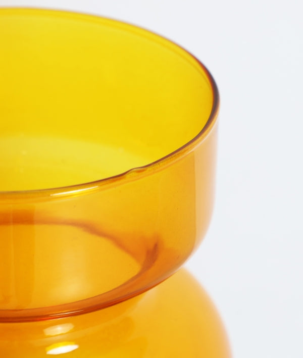 Primer plano del Jarrón de vidrio ámbar brillo 17×17×35 cm - moderno - SOLANGE, jarrón redondo y translúcido de superficie lisa con un pequeño desconchón en el borde.