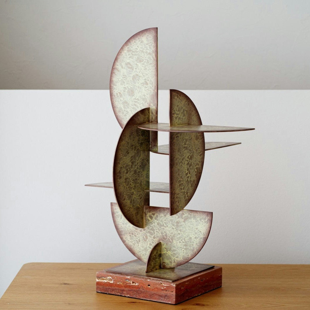 La Figura Decorativa en Metal y Mármol Abstracción N3 es una escultura abstracta moderna con formas semicirculares entrelazadas y textura moteada, montada sobre una base cuadrada. Realza con elegancia cualquier superficie de madera, añadiendo un toque contemporáneo a tu espacio.