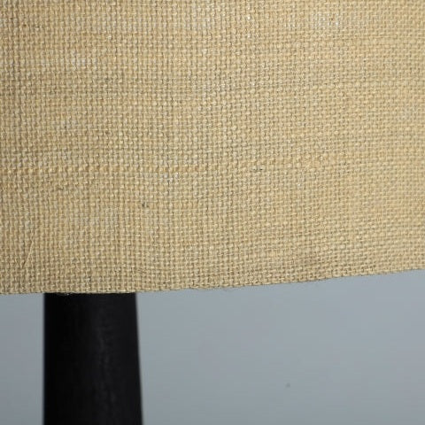 Primer plano del borde inferior de una pantalla de tela texturizada de color beige de la Lámpara de pie en madera de mango Haverslev, sobre un fondo neutro, ideal para la decoración moderna.