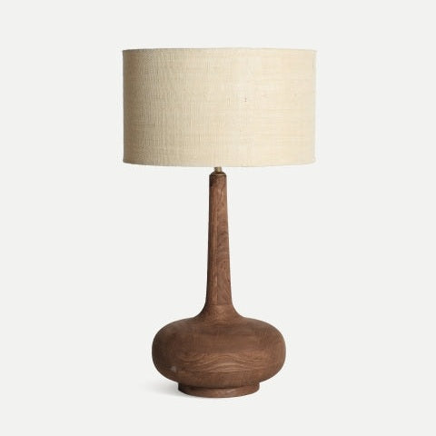 La lámpara de mesa en madera de mango Glogow S presenta una base amplia y redondeada, un cuello alto y delgado, y una pantalla cilíndrica de yute en tono blanco roto.