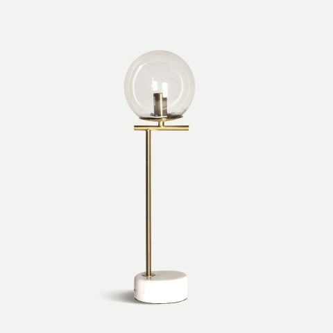 La lámpara de mesa de hierro y mármol Leba, con pantalla de globo de vidrio transparente, tallo de latón y base circular blanca, añade un toque sutil de elegancia Art Decó.