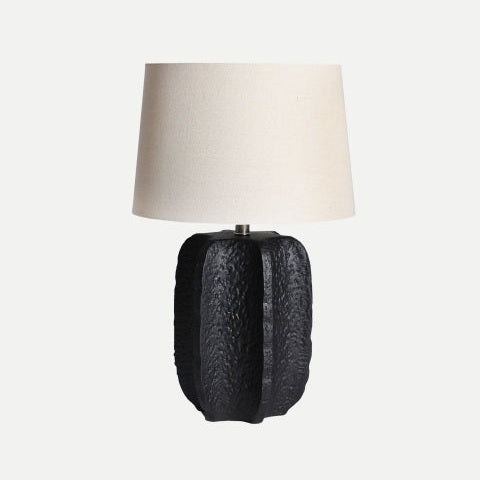 La Lámpara de mesa en cerámica Pamela, con base de cerámica negra texturizada y pantalla blanca, aporta un toque moderno a cualquier espacio sobre fondos claros.