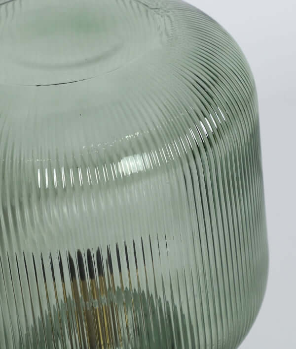 Detalle de la Lámpara de sobremesa cristal verde estriado 27×27×42 cm - moderna - SIRA V, con una pantalla de cristal verde translúcido estriado con líneas verticales texturadas y una superficie lisa reflectante.