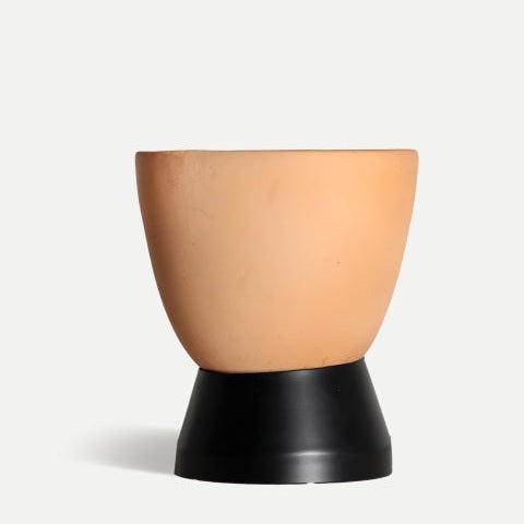 La lámpara de sobremesa en terracota Swahili C destaca con su base plástica negra ligeramente acampanada y diseño elegante, sobre un fondo claro.