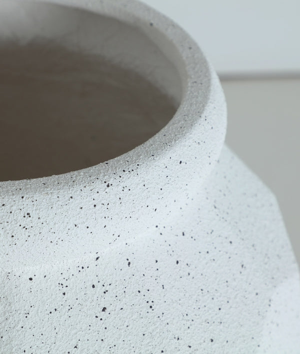 Detalle del borde y la parte superior del Macetero de poliresina blanco roto 46×46×62 cm - moderno - ELMUR L, mostrando su superficie blanca y texturada con motas negras sobre un fondo liso.