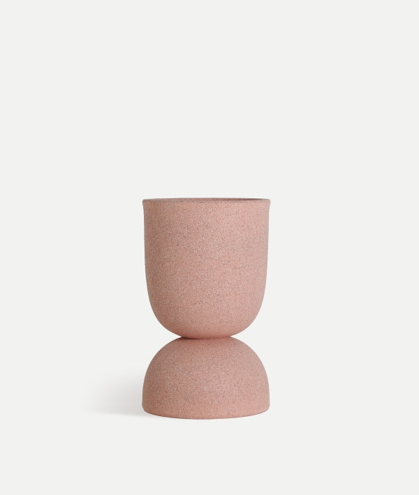 Un moderno macetero de poliresina rosa (37×37×60 cm), NIVOR P, con forma de reloj de arena con dos secciones redondeadas apiladas, expuesto sobre un fondo blanco liso.