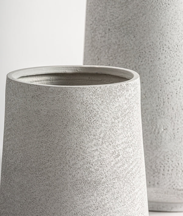 Detalle del Juego de 2 maceteros de cerámica gris - natural - NOVA, que incluye dos maceteros de cerámica gris claro con textura y formas cilíndricas sencillas sobre un fondo liso.