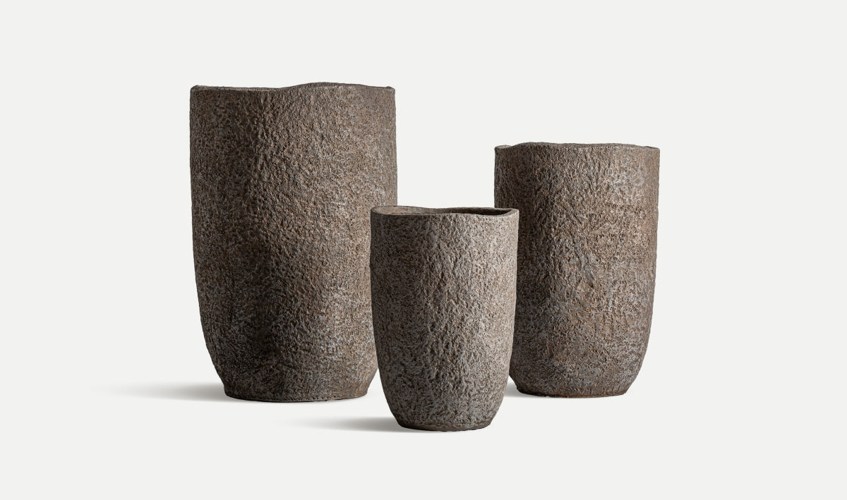 Tres maceteros cilíndricos de cerámica gris rugosa de diferentes alturas del Juego de 3 maceteros de cerámica gris rugosa - natural - ROKA se disponen sobre un fondo blanco liso, creando un elegante juego de maceteros artesanales.