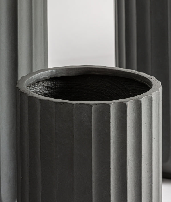 Primer plano de un Juego de 3 maceteros de cerámica estriada gris - natural - TAVO, que presenta un macetero cilíndrico gris con un diseño estriado texturizado, sobre un fondo neutro.