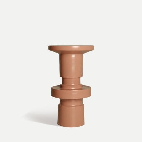 Mesa auxiliar Ivrea en hierro rosa polvoriento, que presenta un diseño geométrico marrón con una base cilíndrica y una tapa circular plana, acabada en un elegante lacado mate, que se muestra sobre un fondo blanco liso.