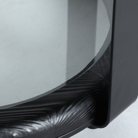 Este primer plano destaca la Mesa auxiliar industrial en madera de abeto Kilde, que muestra un tablero circular de vidrio y una base negra texturizada, que personifica el diseño minimalista. Elaborado con materiales de alta calidad, es ideal para espacios contemporáneos.