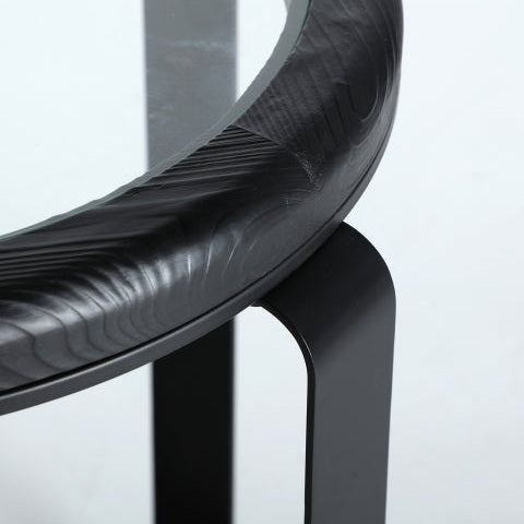 Primer plano de la mesa auxiliar industrial en madera de abeto Kilde con pata de metal negro, borde texturizado y superficie de vidrio, personificando un diseño minimalista con materiales de alta calidad.