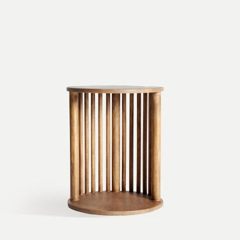 La mesa auxiliar de madera de mango Trevoux presenta un diseño cilíndrico de madera con listones verticales y una base y tablero circulares, sobre un fondo liso. Su elegante construcción encarna la sencilla elegancia del estilo nórdico.