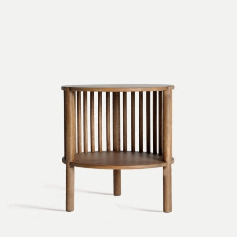 La Mesa auxiliar redonda de madera de mango Trevoux presenta un diseño curvo, rejillas verticales, tres patas y repisa inferior, elaborada en madera resistente de mango y fotografiada sobre fondo blanco.