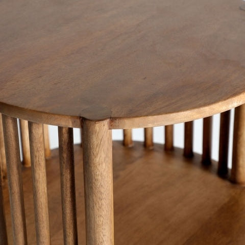 Primer plano de la mesa auxiliar redonda de madera de mango Trevoux, con listones verticales que sostienen el estante superior e inferior, diseñados para resaltar la veta natural y el acabado suave de la madera de mango: una elegante mesa auxiliar redonda.