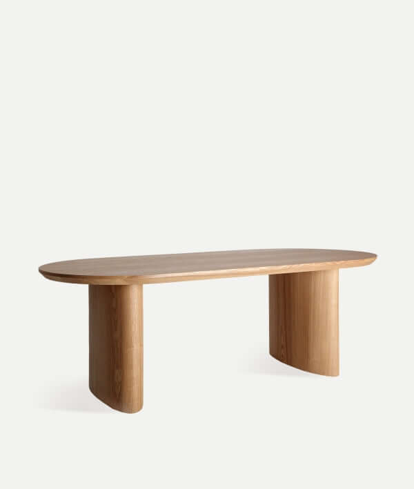 La Mesa de comedor elíptica SOMA en DM y chapa de nogal marrón (220×100×76 cm) presenta un diseño moderno con tapa rectangular redondeada y dos patas anchas curvadas, sobre fondo blanco.