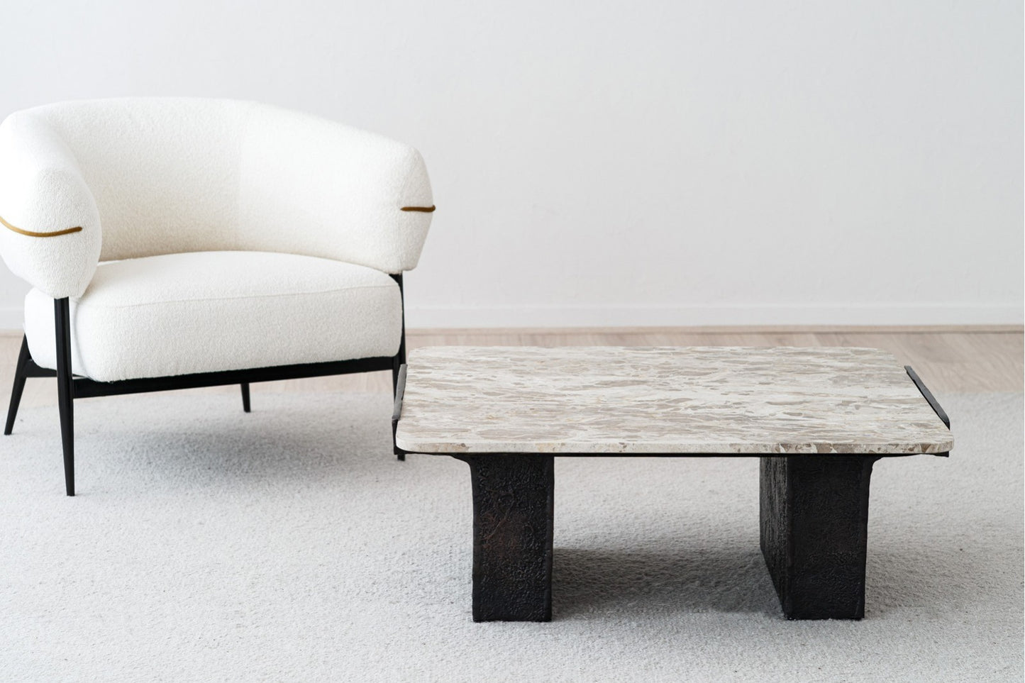 Un sillón blanco tapizado se sitúa junto a la Mesa de centro cuadrada de mármol-metal 90×90×35 CM (acabo óxido), añadiendo elegancia moderna sobre una alfombra de color claro.