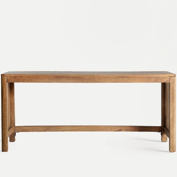 La mesa de centro en madera de mango Trevoux exhibe un estilo nórdico con su diseño simple de madera y su tapa plana, que se destaca elegantemente sobre un fondo liso.
