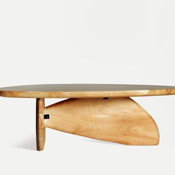 La mesa de centro en madera de acacia Wighill es contemporánea con una superficie ovalada y presenta un diseño de base triangular asimétrico sobre un fondo liso.