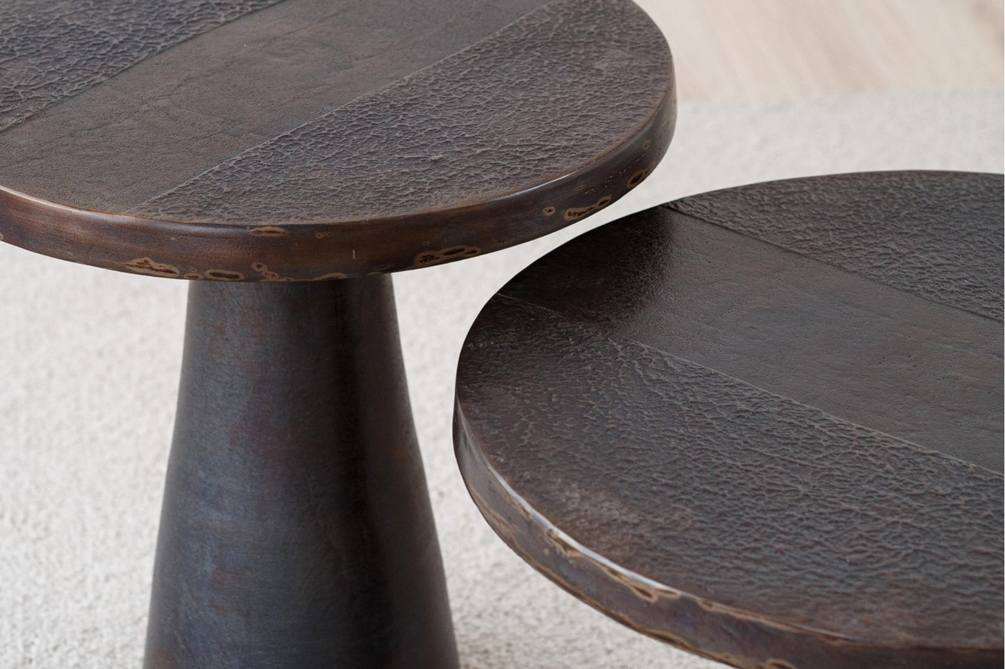 Dos mesas auxiliares redondas de metal (58×44 / 50×51 cm) con acabado en bronce envejecido y diseño cónico contemporáneo, BRONZ, se alzan juntas sobre una ligera alfombra-mesa auxiliar perfecta para espacios de vida modernos.