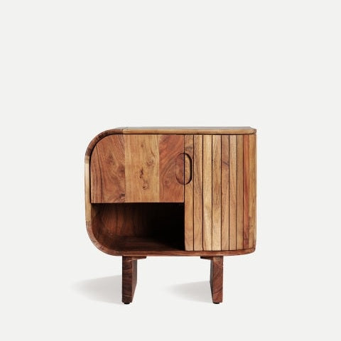 La mesita de noche Blesle, de madera de acacia, presenta un diseño de madera con bordes redondeados y listones verticales en un lateral. Ofrece un práctico espacio de almacenamiento gracias a un compartimento cerrado sobre estantes abiertos y se alza elegantemente sobre cuatro patas, lo que la convierte en una mesita de noche elegante e ideal.