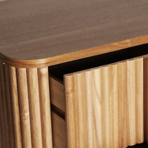 Primer plano de una mesita de noche Skagen elaborada con madera de paulownia y hierro, con un cajón ligeramente abierto. La textura acanalada de la superficie y los paneles laterales evoca un elegante estilo nórdico.