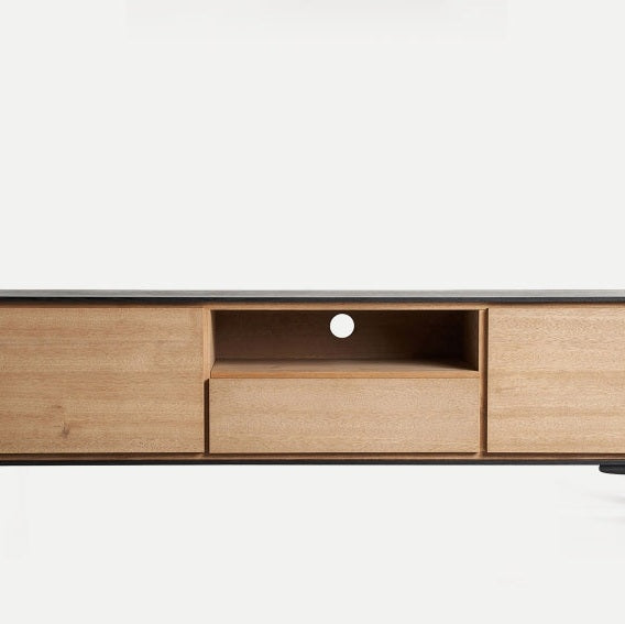 El mueble TV en madera DM y hierro Brussa presenta una elegante cubierta negra, dos gabinetes laterales, un estante intermedio con un orificio circular para cables y un cajón debajo: una encarnación del elegante diseño industrial.