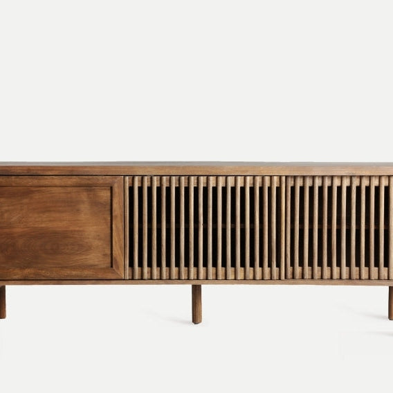 El mueble TV en madera de mango Trevoux presenta un aparador de madera con tres secciones: una puerta sólida a la izquierda y dos puertas con listones a la derecha, sostenidas por cuatro patas cilíndricas, que incorporan el estilo nórdico moderno en un diseño elegante y duradero.