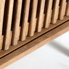 Primer plano de las lamas verticales de madera del Mueble TV de mango Trevoux, proyectando sombras sobre una superficie clara inferior. Este detalle captura la esencia del estilo nórdico moderno.